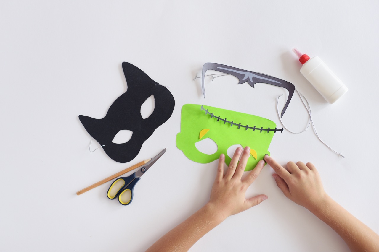 Making masks paper holiday Halloween Monster's mask Black cat Hands top view